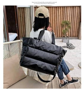 Outdoor shot of a black quilted puffer tote bag shown on a model for travel and fitness