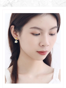 Close-up of a model wearing cute egg-shaped earrings with white and yellow enamel finish