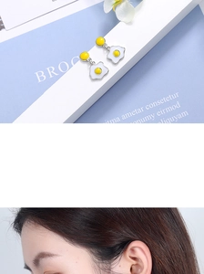 Detailed view of handmade poached egg stud earrings with white and yellow enamel detailing