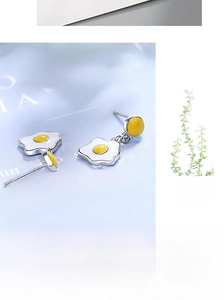 Detail view of handmade enamel fried egg stud earrings with cute asymmetrical design