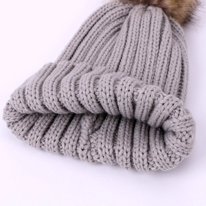 Bonnet tricoté gris pour enfants avec un pompon moelleux en fausse fourrure brune