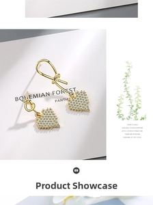 Detailed close-up of gold asymmetrical heart earrings with pavé crystals on a card