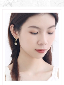 Close-up of heart-shaped gold earrings with diamonds worn by a model in profile