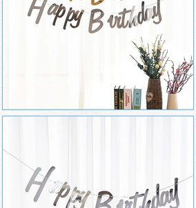 Silver Happy Birthday script banner hung against a white curtain for party decor