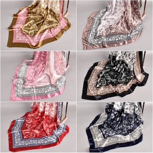 Variety of satin silk square scarves with paisley patterns on golden display stands