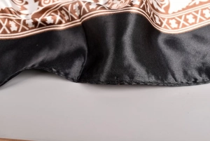 Detailed macro view of black satin square scarf with vintage golden chain print patterns