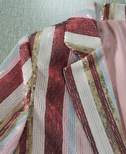 Dettaglio blazer a righe con paillettes colorate e fodera in raso rosa sul colletto