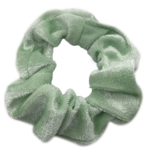 Chouchou en velours vert clair pour femme avec texture plissée sur fond blanc neutre