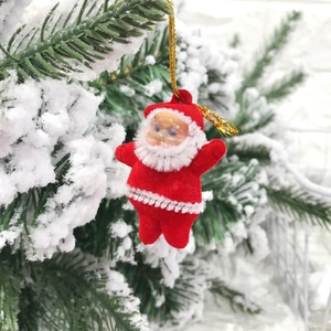 Detail of red flocked Santa Claus hanging ornament on a snowy Christmas tree branch
