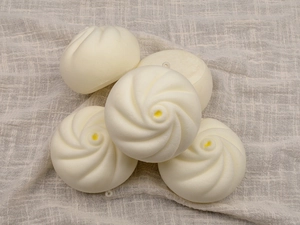Detailed view of 5 squishy simulation steamed buns with soft PU texture on linen