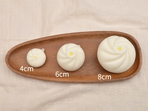 Three sizes of slow rebound bun toys on a wooden tray with 4cm, 6cm, and 8cm dimensions
