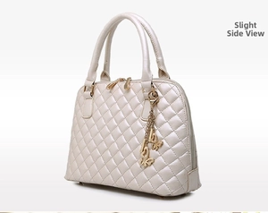 Detail of cream quilted tote bag with golden zipper and a butterfly metal charm