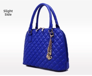 Detail view of the quilted blue shell bag featuring a gold butterfly charm and dual zippers