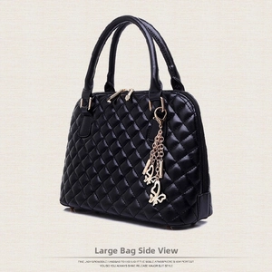 Side view of black quilted shell handbag with gold zipper and butterfly tassel detail