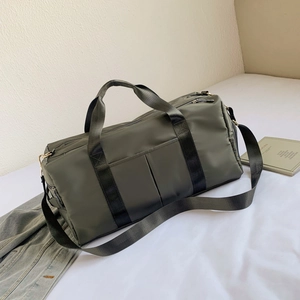 Army green waterproof gym bag with dual handles and shoulder strap on white bedding