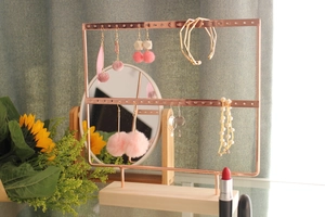 Rose gold metal jewelry stand with pine wood base shown on a dresser with sunflowers