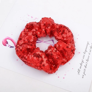 Close-up of a red sequin scrunchie hair tie on a white flamingo card background