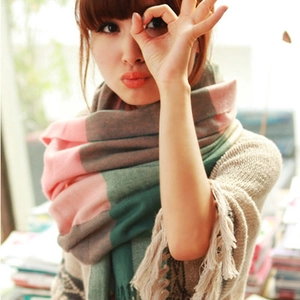 Detail of pink and green plaid scarf featuring thick tassels and autumn winter texture