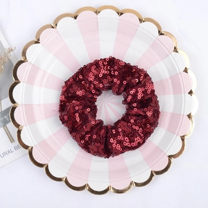 Dark red sequined hair scrunchie with shiny fish scale pattern on a decorative plate
