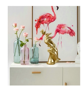 Detailed close-up of matte gold resin hand statue holding a rose on a white cabinet