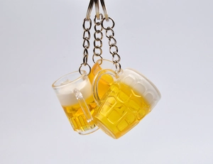 Dettaglio di tre portachiavi a forma di boccale di birra in resina con schiuma e anello in metallo