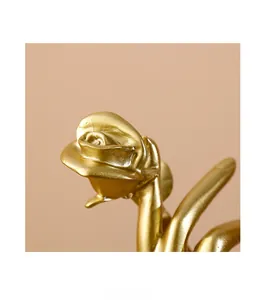 Detailed close-up showing the layered petals and matte gold texture of the rose sculpture