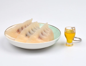 Dettaglio di modelli di gnocchi in resina e portachiavi a boccale di birra in una ciotola