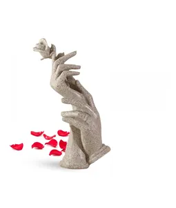 Macro view of sandstone resin hand-held rose sculpture with red scattered petals