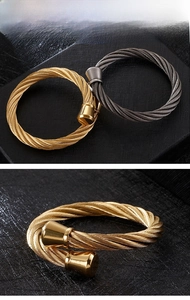 Detail of cable style stainless steel open bangle in gold and gunmetal finishes