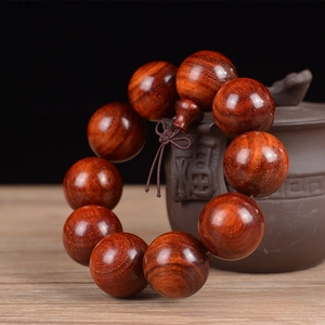 Close-up of 25mm sandalwood beads with fine grain on a traditional clay teapot