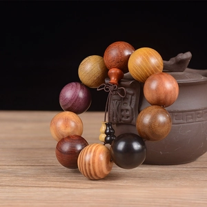 Macro detail of 25mm mixed wood beads bracelet with gourd charms on a clay teapot