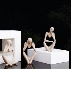 Close-up of three sandstone abstract thinker statues on white geometric stands