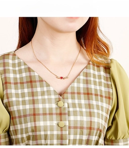 Détail d'un collier avec pendentif cœur doré et cristaux rouges porté par un mannequin