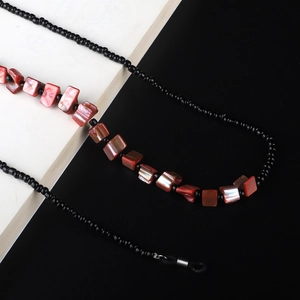 Detail of beaded sunglasses chain with red shell fragments and black beads with silver ends