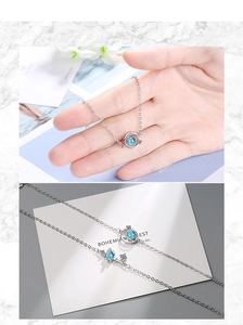 Detail of silver planet bracelet with blue stone and zircon accents on a wrist