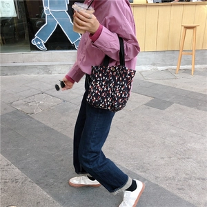 Dettaglio della borsa tote in tela a fiori portata da una modella in uno stile casual street