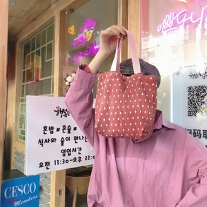 Dettaglio della borsa in velluto a coste a pois con manici in tela rosa in scena urbana