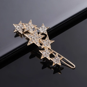 Macro shot of gold star-shaped hair clip with shimmering rhinestones on black background