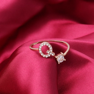 Adjustable gold letter Q ring with sparkling crystals on red silk background