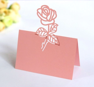 Detailed close-up of a laser-cut pink rose place card for elegant wedding table settings
