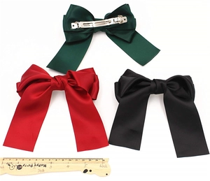 Detail of satin bow hair clips in green, red and black with metal spring back fasteners