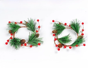 Detailed view of two Christmas napkin rings featuring pine needles, red berries, and cones