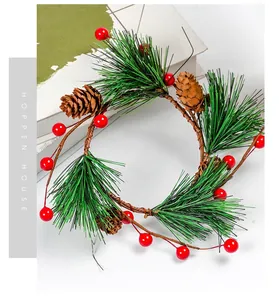 Close-up of artificial pine needles, red berries and pine cones on a rustic vine wreath