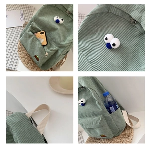 Detail view of green corduroy backpack with large eye decor and side water bottle pocket