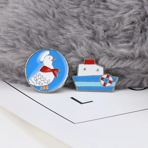 Detailed view of cartoon duck and anchor ship enamel pins on a soft textured background