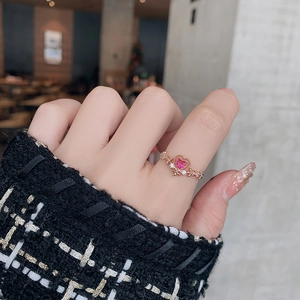 Detail of rose gold ring with pink heart crystal and pavé floral accents on model's finger
