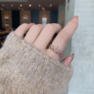 Close-up of stacked rose gold rings featuring crystal flower clusters and blue stones