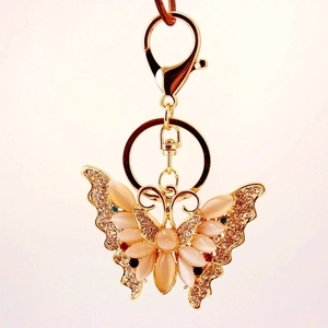Golden butterfly keychain with opal stone and sparkling crystal accents on a white background