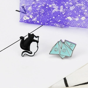 Detail view of cartoon black and white cat enamel pins with origami geometric design