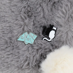 Enamel pin set featuring black and white hugging cats and a blue origami motif
